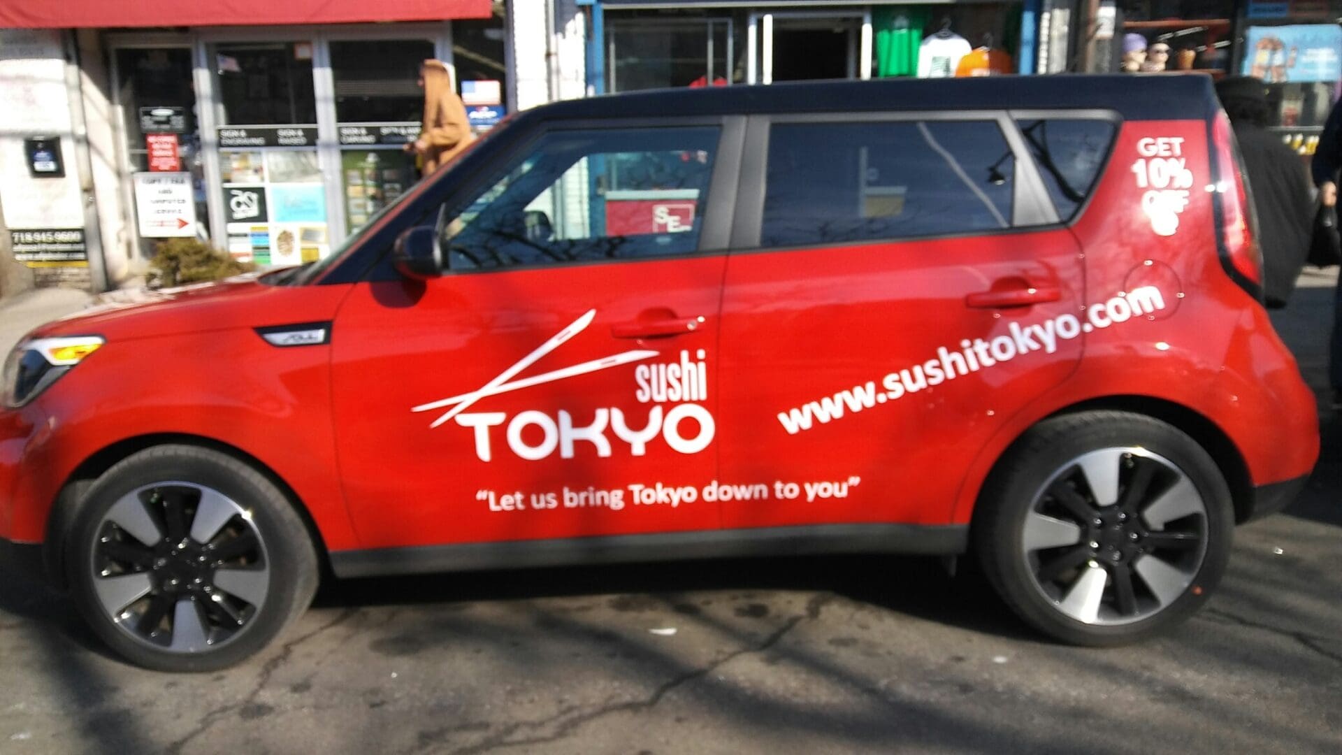 A red car with sushi tokyo written on it.