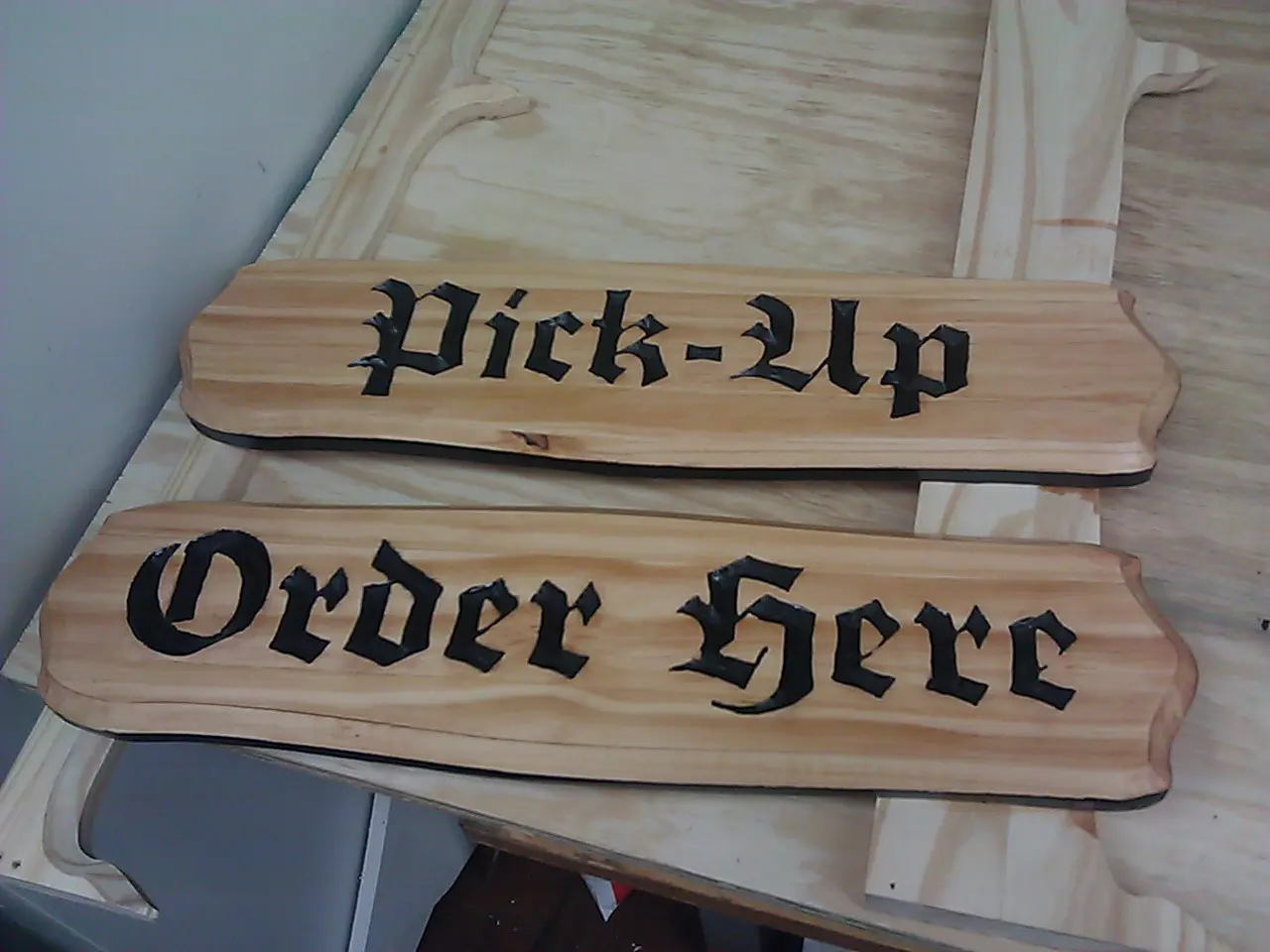 A wooden sign that says pick up and order here.