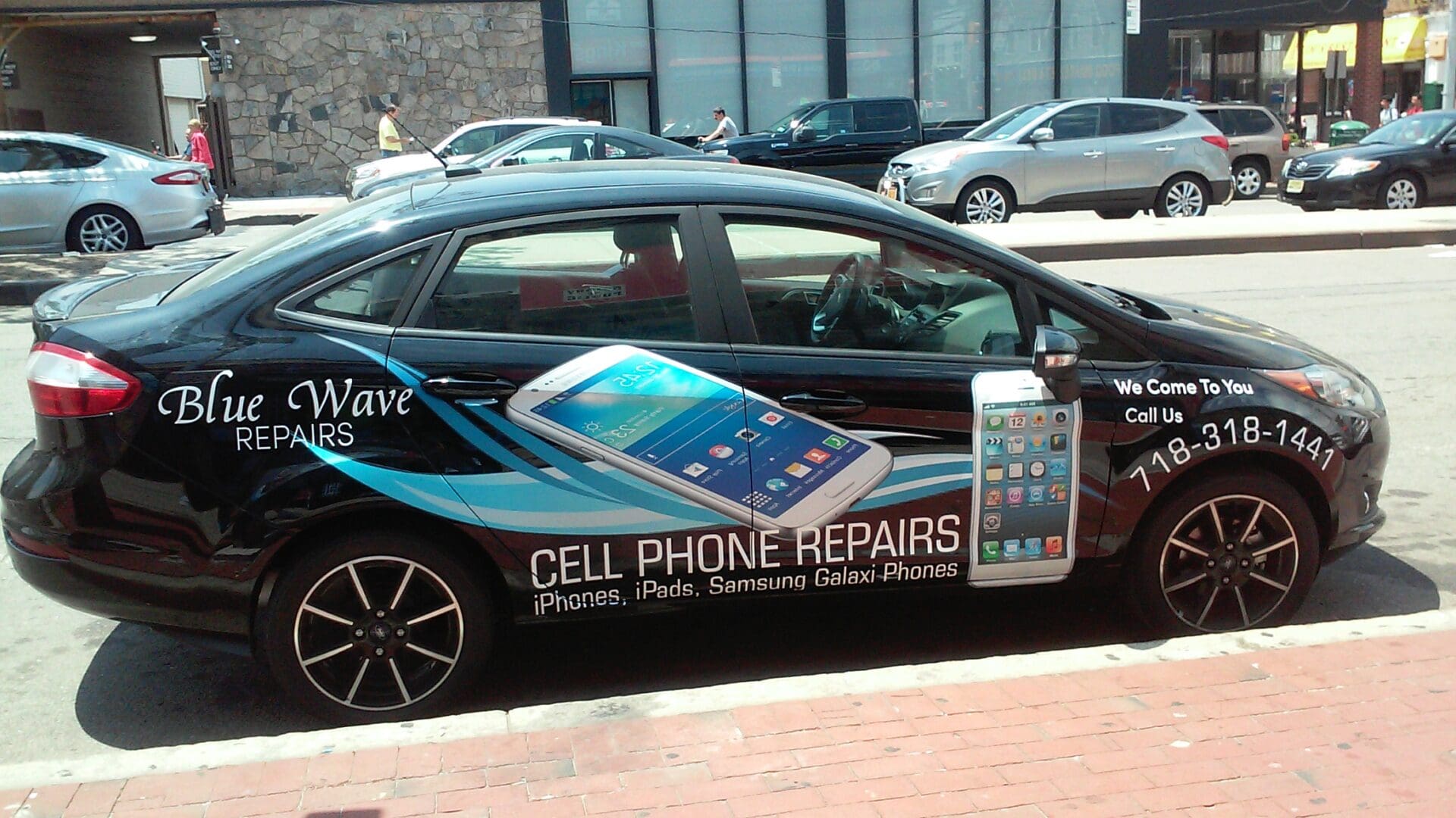 A black car parked on a street, adorned with advertisements for ADP USA Solutions Gallery, featuring imagery of phones and contact information.