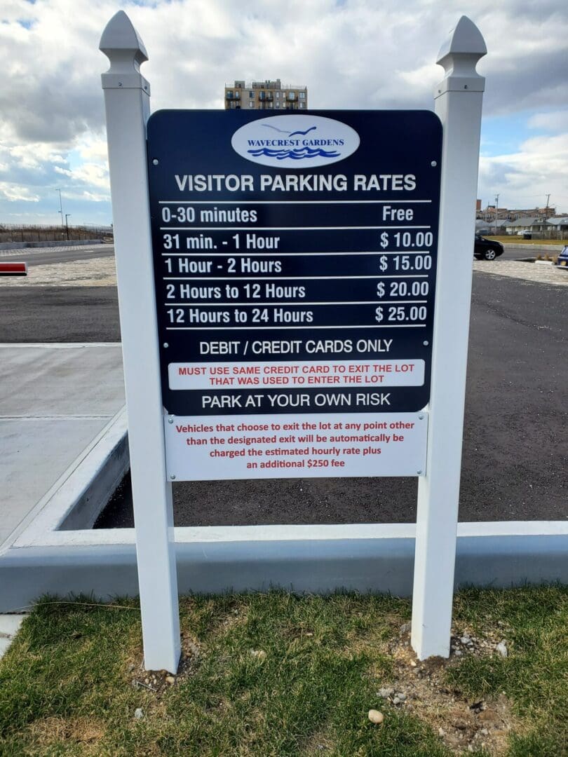 Visitor parking rates sign at ADP USA Solutions Gallery, listing various time-based fees and payment information, set against a cloudy sky backdrop.