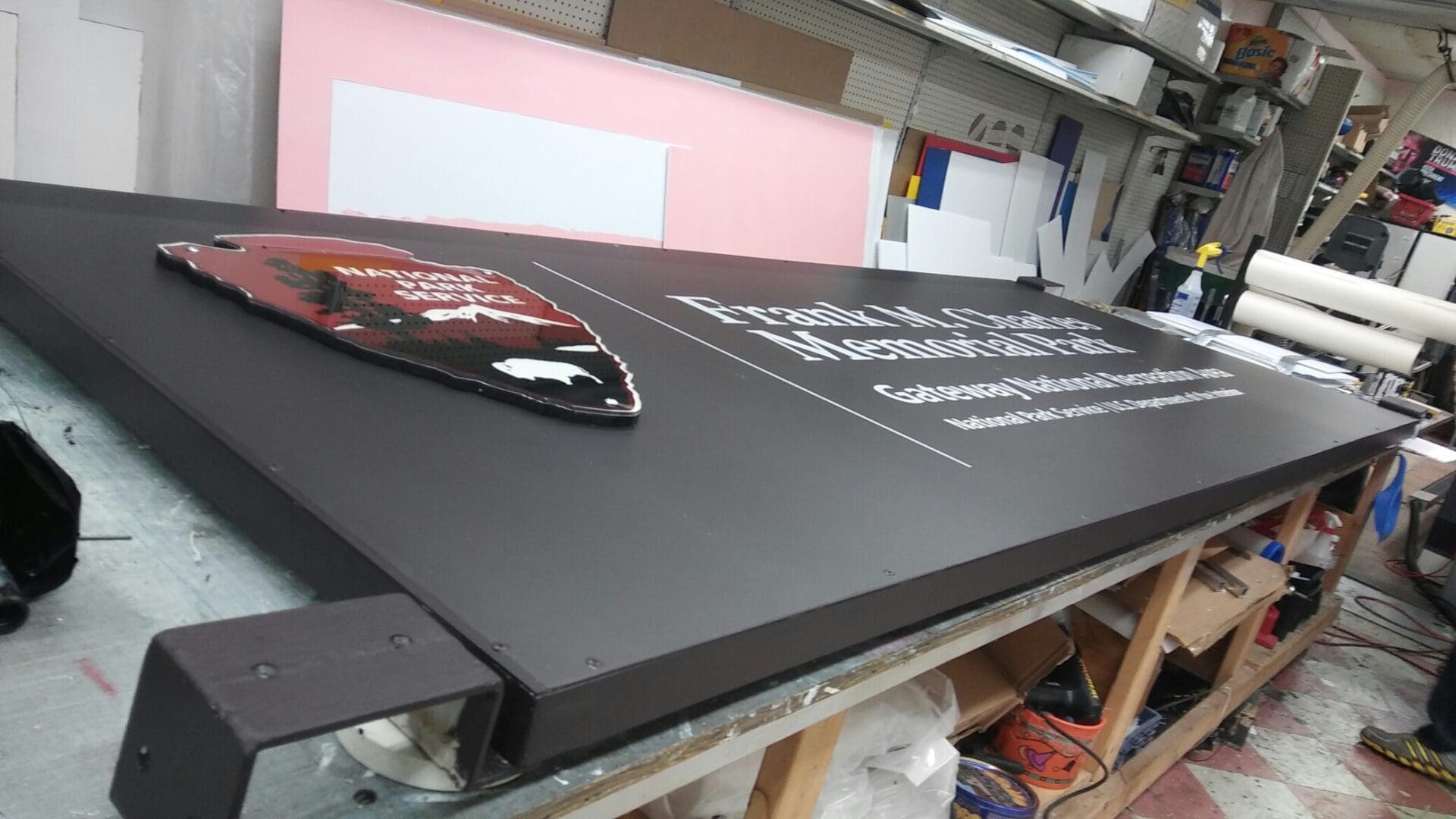 Large black sign with white text and a colorful graphic design for ADP USA Solutions Gallery, laying on a worktable in a workshop.