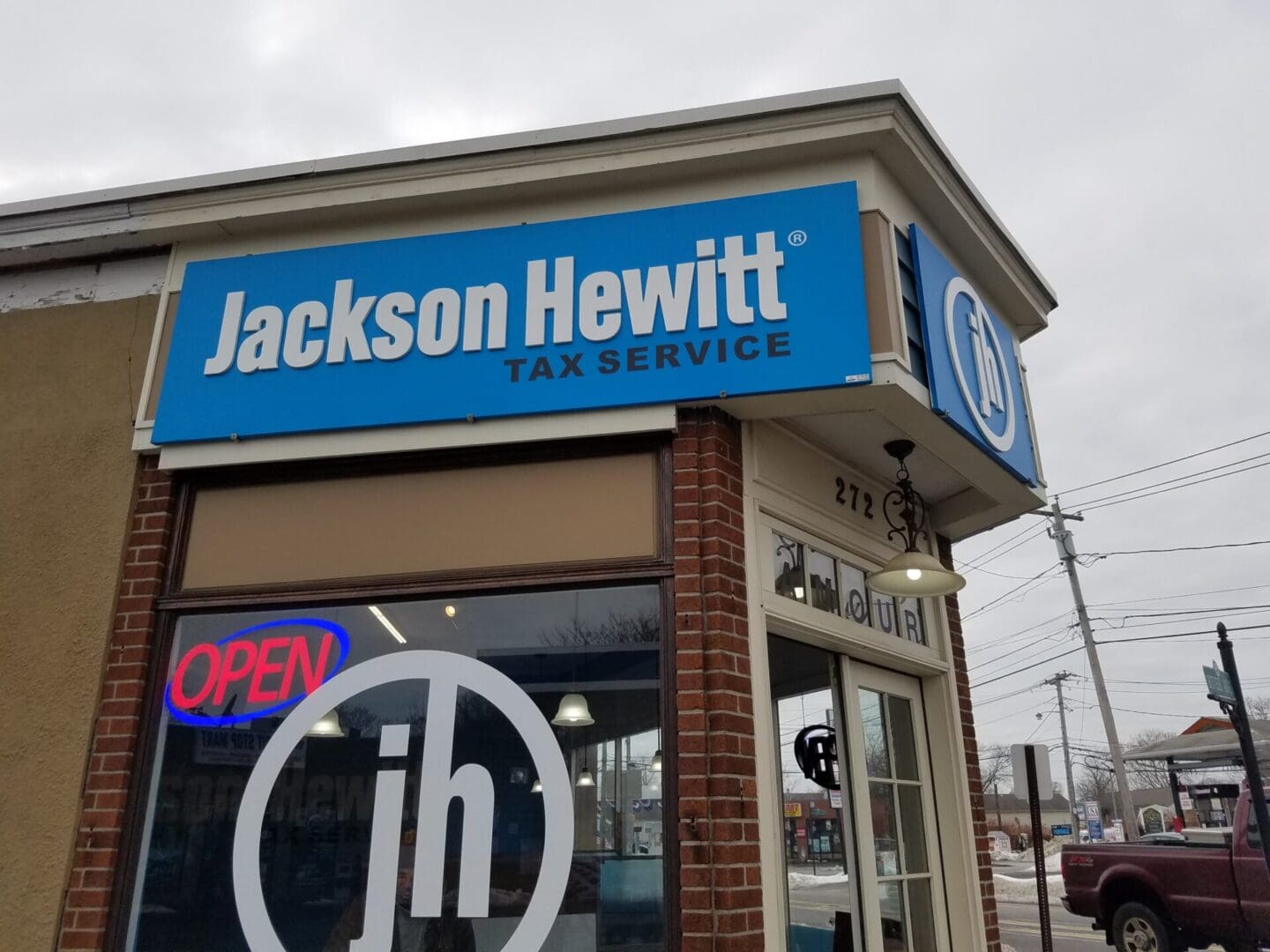 Storefront of a Jackson Hewitt tax service office with a blue sign, located on a cloudy day at ADP USA Solutions Gallery.