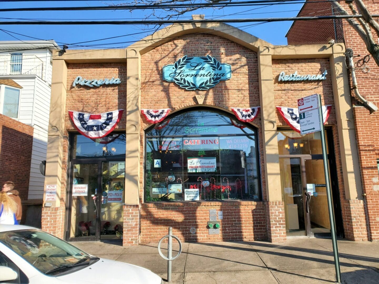 Front view of ADP USA Solutions Gallery and La Fontana del Mare restaurant with patriotic banners and a clear blue sky.