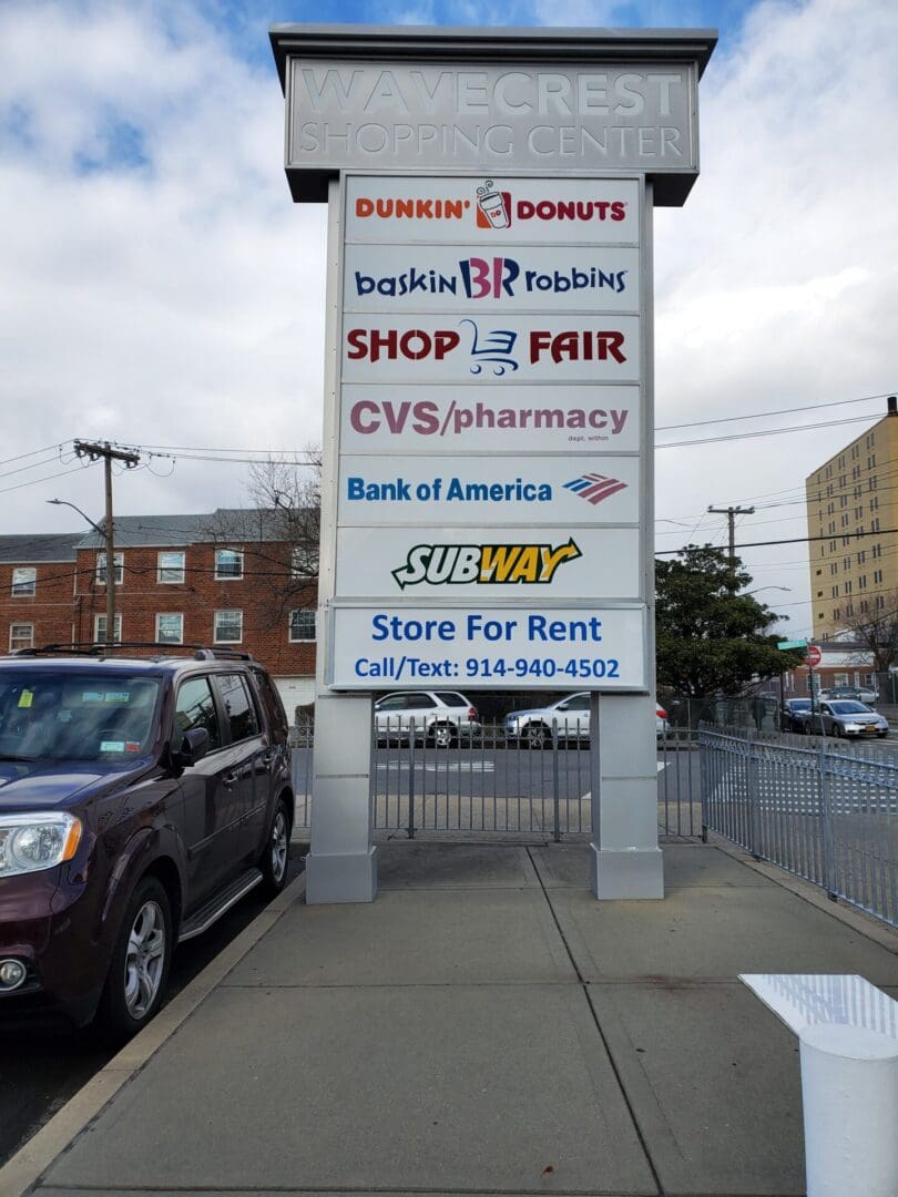 A street view of the wavecrest shopping center sign listing multiple businesses including Dunkin’ Donuts, Baskin Robbins, CVS, Bank of America, and Subway near the ADP USA